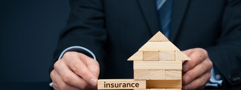 Assurance Property (family house) insurance protection concept. Insurance agent complete wooden model of the house with last piece with text insurance.