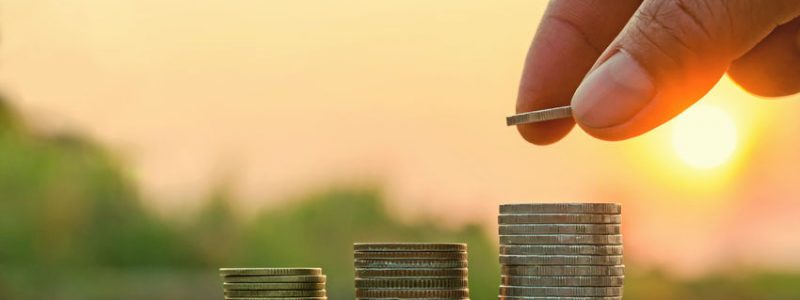 73940272_s 73940272 - hand putting coin on coins stack with concept idea saving money and nature sunset background